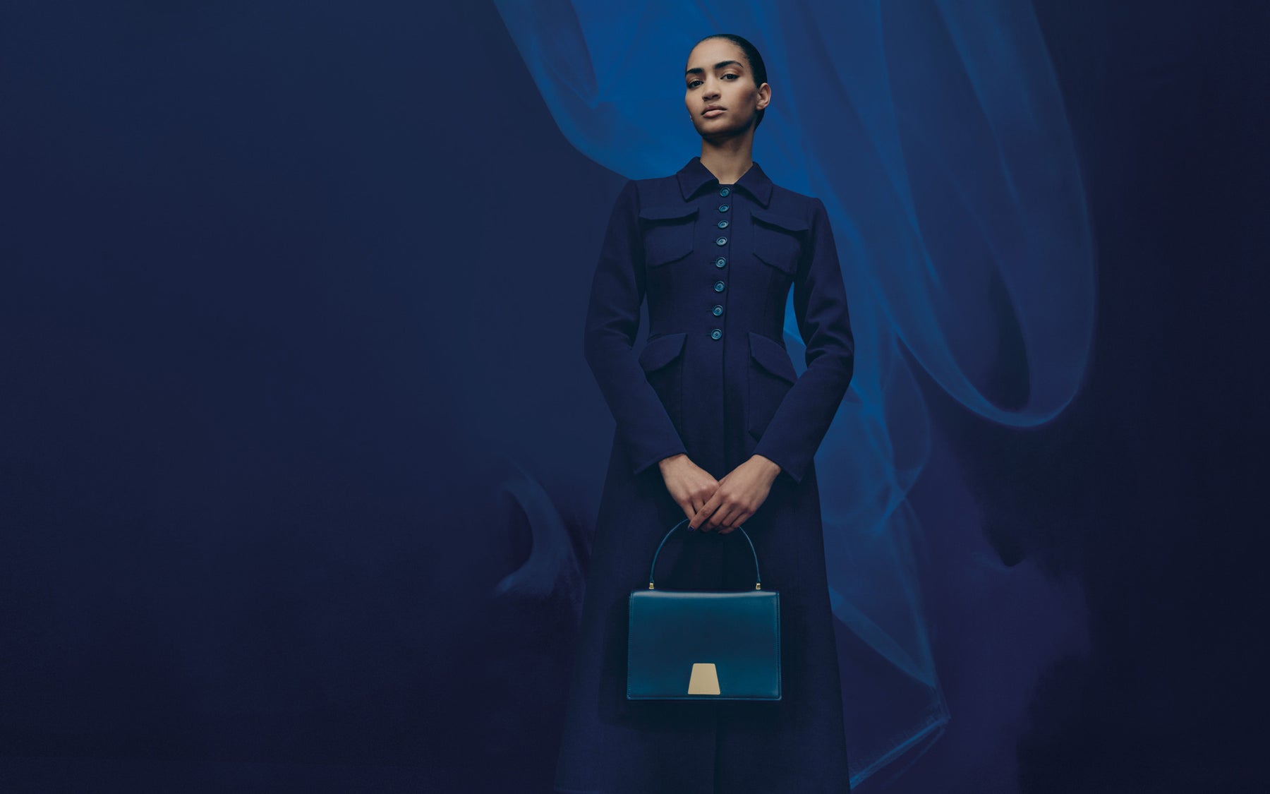 Akris FW 2025 collection distills the magic of the blue hour into wearable form. Tailored coats, feather skirts, and softly structured dresses define the silhouette. 