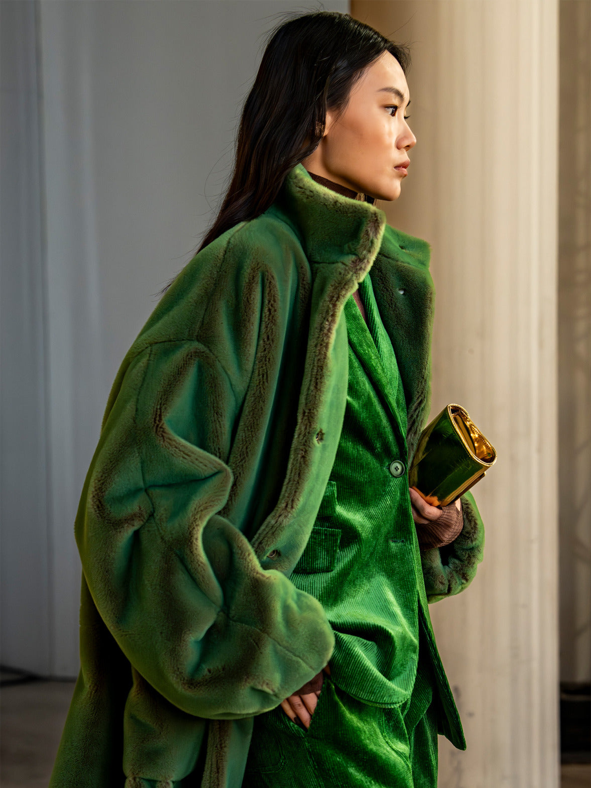 Look from the Akris punto Fall 2026 collection featuring a vibrant green tailored ensemble layered with a sculptural shearling coat and modern occasion elegance.