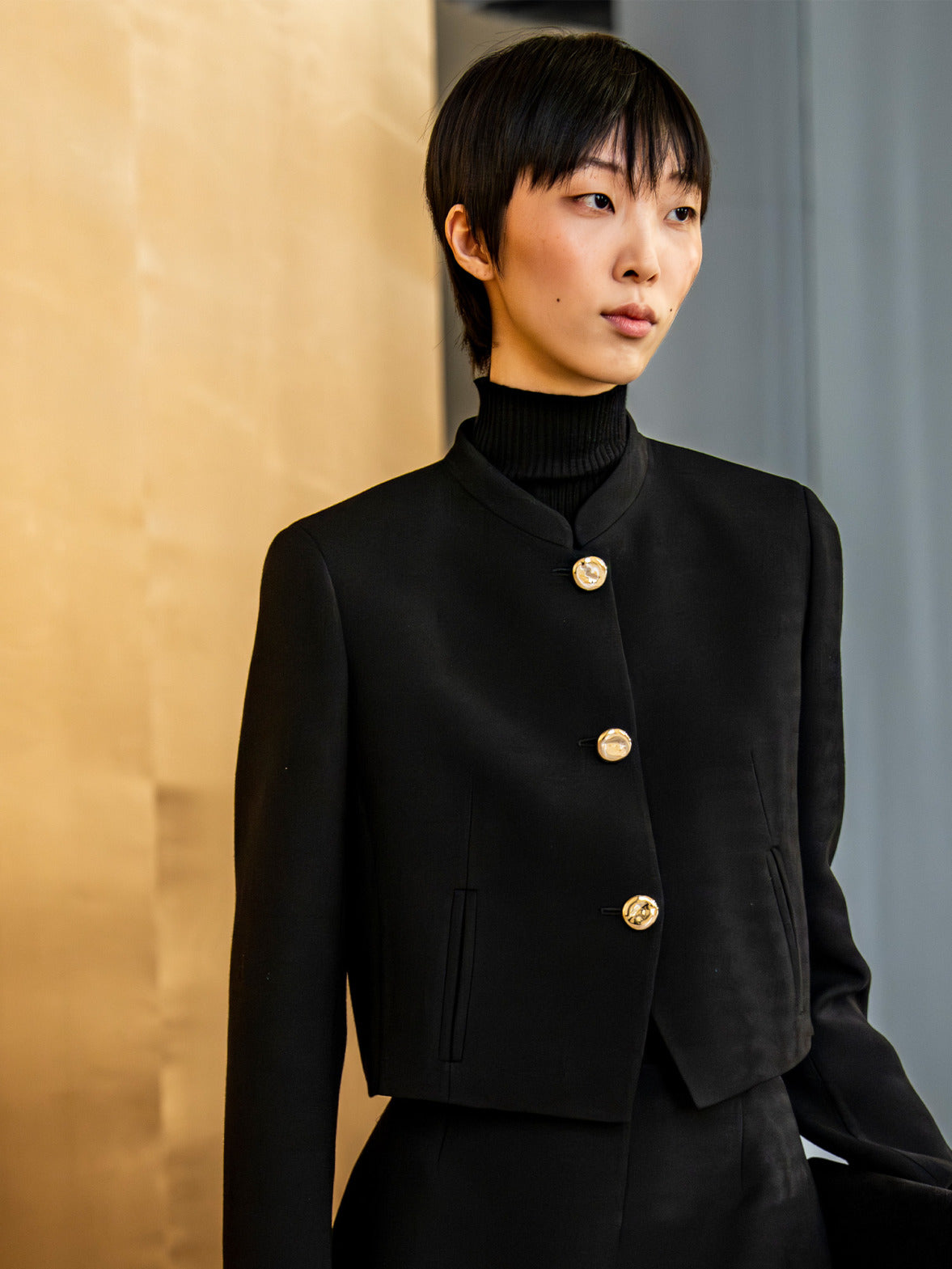 Look from the Akris punto Fall 2026 collection featuring a structured cropped jacket with gold-tone buttons and refined tailoring for modern understated elegance.