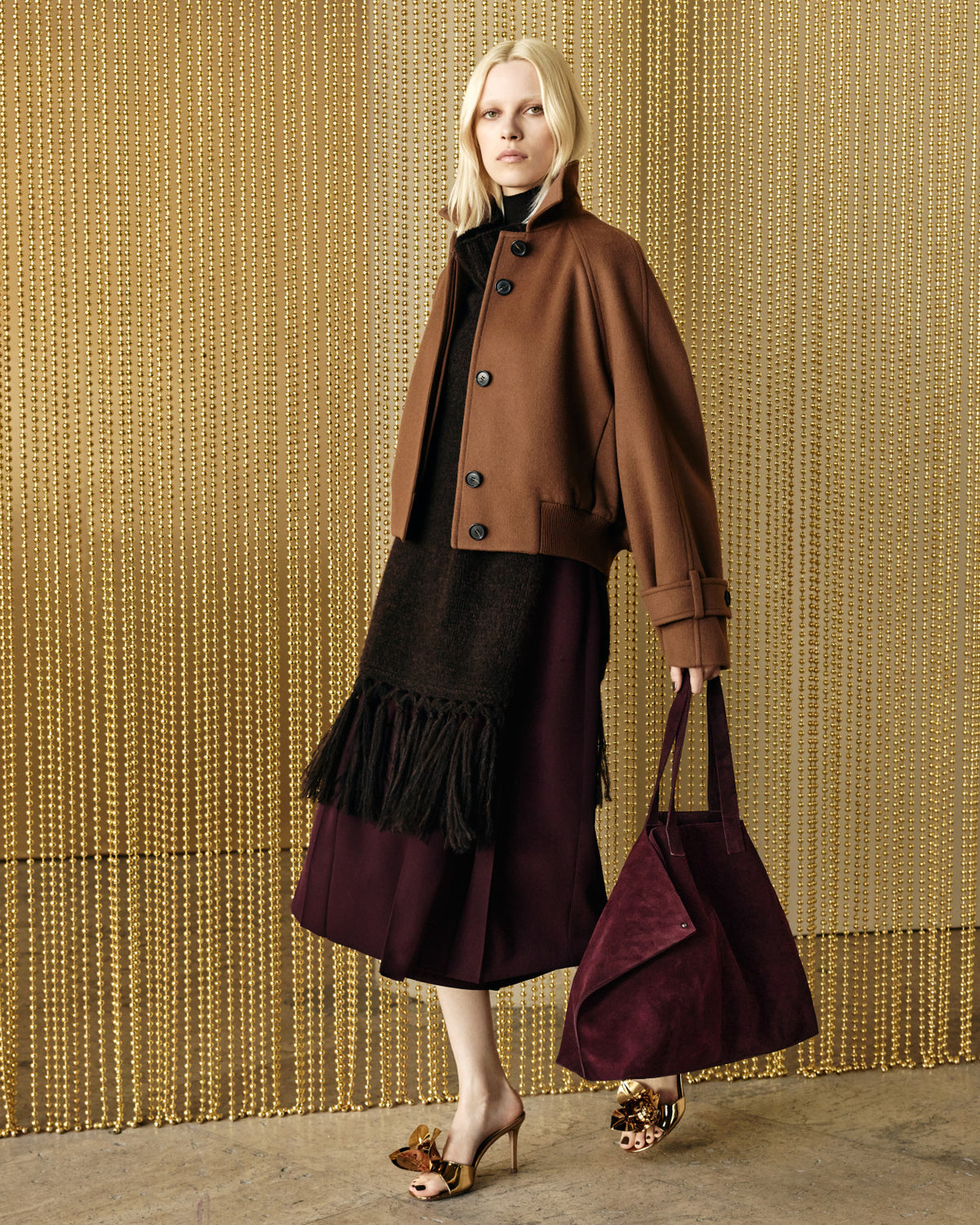 Akris Fall 2026 look featuring a sculptural silhouette set against an Olga de Amaral-inspired textile installation. The collection merges artisanal craftsmanship, tactile materials, and modern elegance.