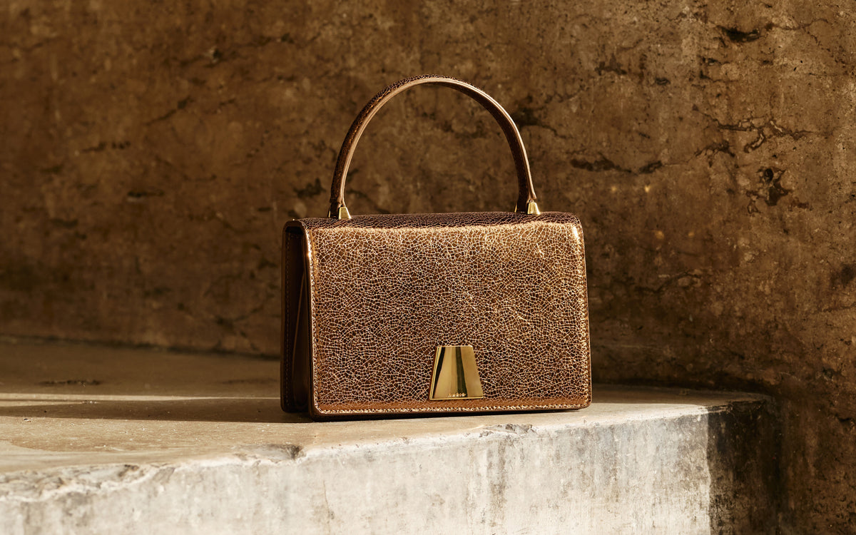Akris Alice Top Handle Bag in metallic bronze leather, featuring a structured silhouette and signature trapezoid closure.