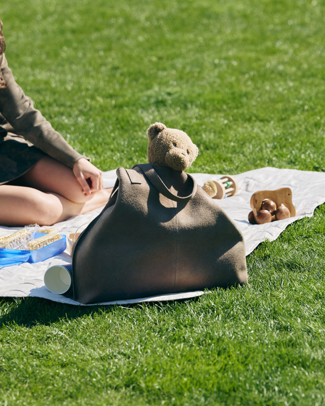 Iconic Akris Ai bag as a perfect Mother's Day gift, pictured on a picnic blanket with toys.