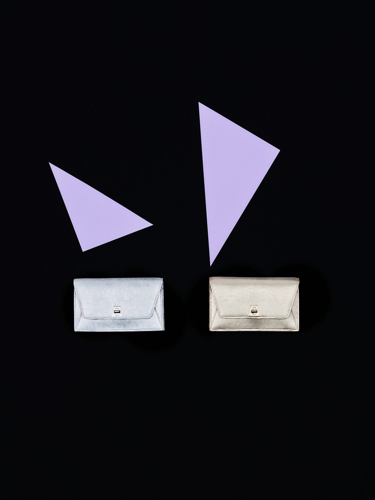 Discover the evening glamour of the Akris Pre-Fall collection, showcasing the elegant Anouk clutch bags in striking metallic silver and gold leather finishes. Set against a minimalist black background with sharp lavender geometric accents, these luxury accessories exude modern sophistication. Elevate your formal style with timeless Swiss craftsmanship.