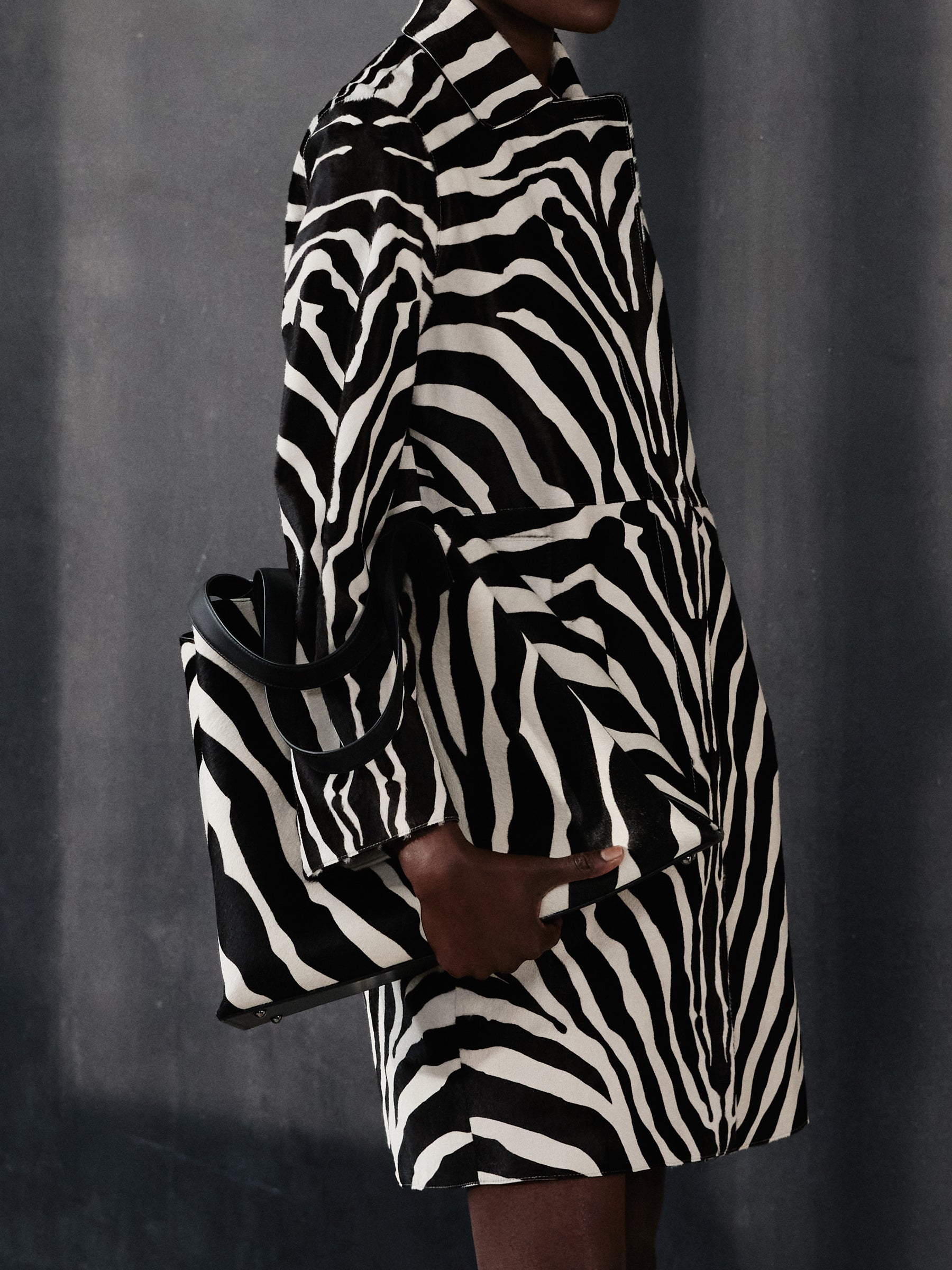 Make a bold statement with the Akris Pre-Fall collection, showcasing a striking total look in zebra print. Pair the luxury graphic-patterned coat with the iconic, matching Ai tote bag in pony-styled calf skin. Embrace monochromatic elegance and Swiss craftsmanship to elevate your seasonal wardrobe.