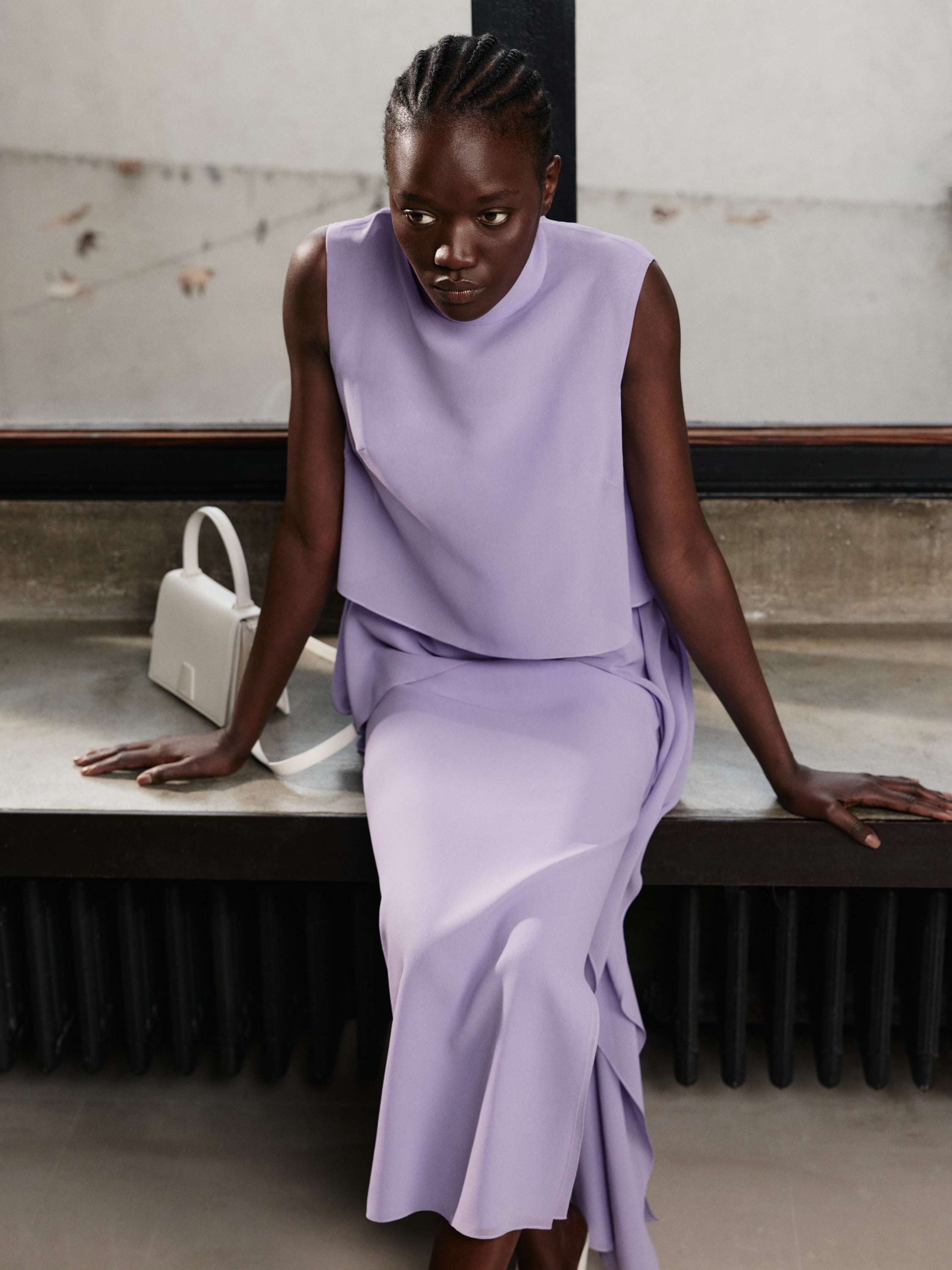 Embrace effortless refinement with the Akris Pre-Fall collection, featuring a stunning monochromatic look in a delicate wisteria violet shade. Complete the elegant draped ensemble with the minimalist chic of the white Alice handbag. Discover the perfect balance of fluid tailoring and timeless luxury craftsmanship.