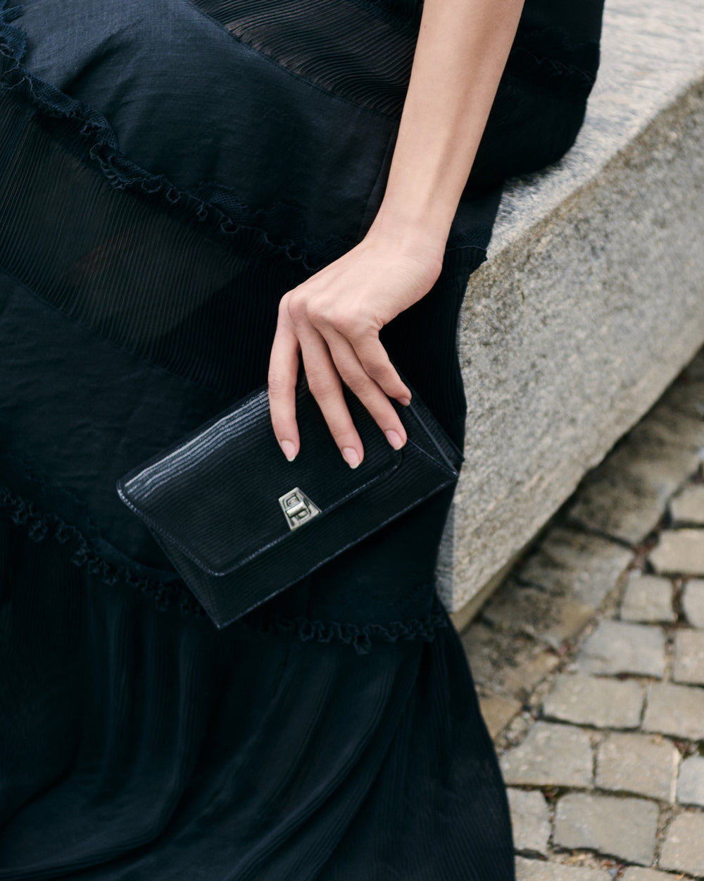 Black clutch bag from Akris in the hand of a lady.